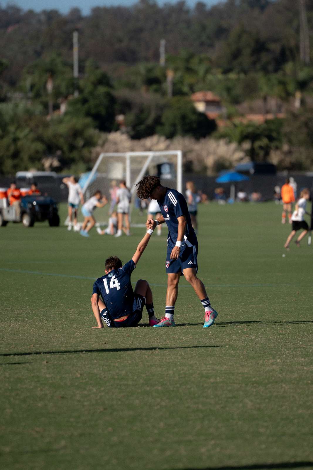 A player helping a teammate up off the pitch