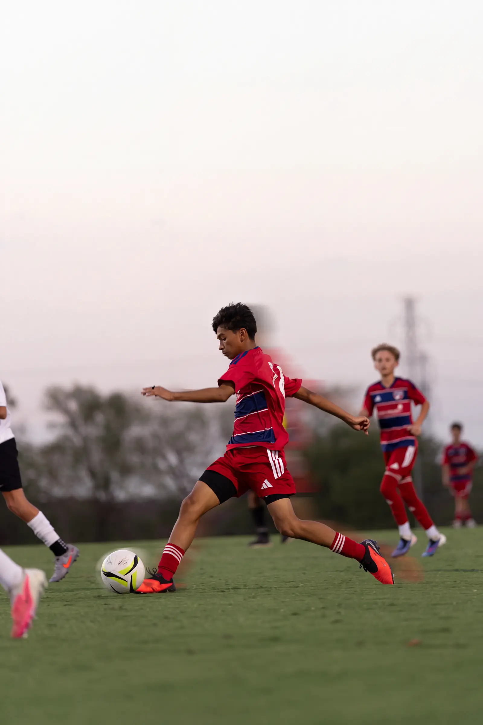 FC Dallas player striking the ball at golden hour